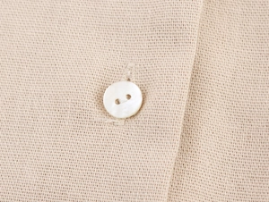 Detailed close-up of textured chunky knit fabric and button detail on a beige shirt