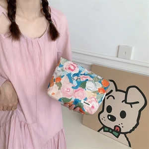 Detail of floral cotton makeup bag featuring intricate embroidery and branded woven label