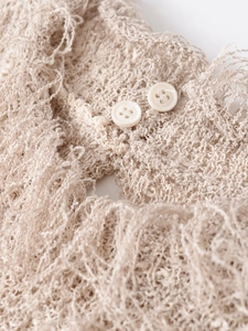 Macro shot of beige knitted texture and two white buttons on a stylish fringe vest