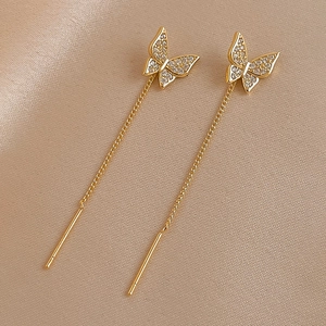 Elegant gold butterfly chain drop earrings with zircon crystals on champagne silk background