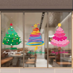 Three colorful artistic Christmas tree window decals applied on a glass storefront