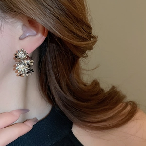 Close-up of floral silver earrings with sparkling crystals worn by a model