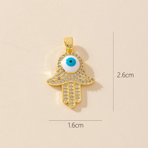 Macro view of gold Hamsa hand pendant with blue evil eye and zircon inlay, size 2.6x1.6cm