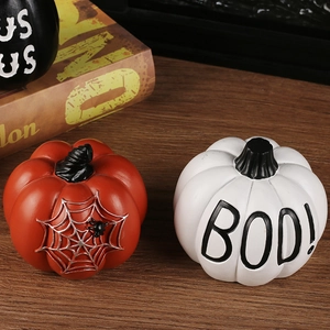 Three decorative Halloween resin pumpkins on a wooden table with spooky artistic patterns