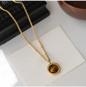 Detail of vintage golden twist chain necklace featuring a round brown tiger eye pendant