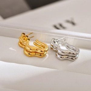 Macro shot of wavy irregular U-shaped stainless steel earrings in gold and silver