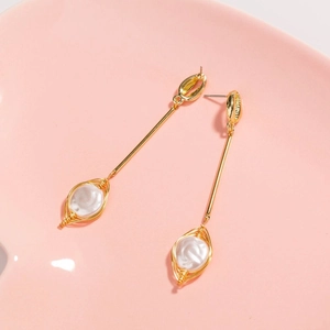 Detailed macro view of long shell pendant earrings with wire wrapped faux pearl detail