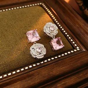 Detail of silver flower earrings with pink square crystals on green velvet tray