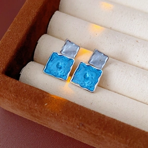 Macro detail of geometric square blue enamel earrings set in polished silver frames