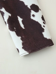 Close-up of animal print knit fabric showing cow pattern and stitched cuff detail