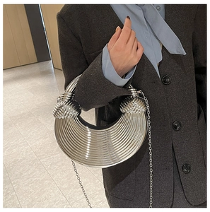 Detailansicht einer silbernen Mondsichel-Handtasche mit Rillenstruktur und Metallgriffen