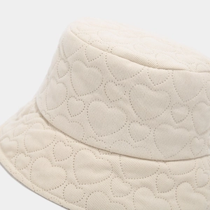 Detail shot of beige corduroy bucket hat with heart quilting and grid texture pattern