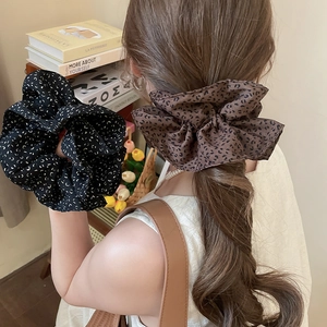 Detail of fluffy leopard print and floral scrunchies on a model for hair styling
