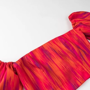 Detail des schulterfreien Oberteils mit rot-violetten Streifen und Nahtdetails am Ausschnitt