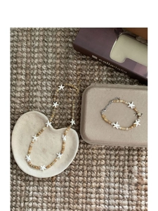 Detail view of beach style beaded necklace and bracelet set with white starfish charms