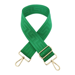 Macro view of bright green jacquard shoulder strap with geometric texture and gold hardware