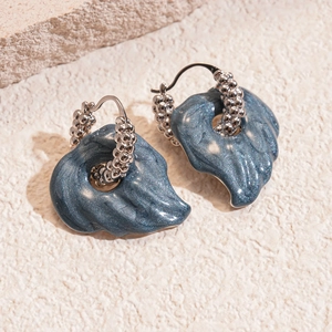 Detail view of deep blue resin leaf earrings with sparkling finish and silver textured hoops