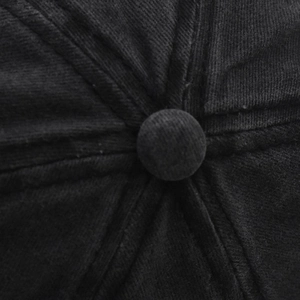 Close-up of the cotton twill top button and stitched seams on a black baseball cap