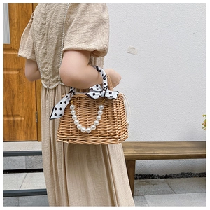 Detail of hand-woven straw bag with elegant pearl handle and polka dot scarf decoration