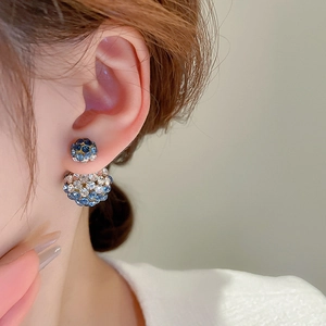 Close-up of elegant double-ball stud earrings with blue and white pavé crystals