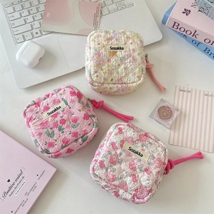 Quilted cotton sanitary pad storage bags in pink floral designs on a white desk