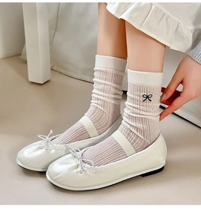 Close-up of white ribbed crew socks with a black bow paired with ballet flats