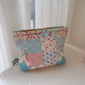 Detailed macro of floral quilted fabric texture and stitching on the vanity bag