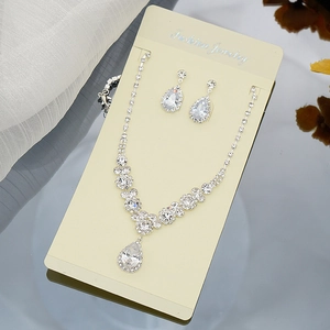 Macro detail of bridal teardrop zircon necklace and earrings set on jewelry display card