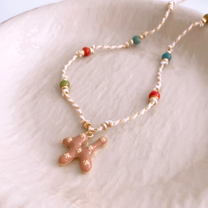 Detail of beaded necklace featuring a brown pendant with gold flowers and colorful beads