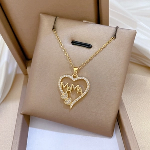 Close-up of a gold heart pendant with MAMA letters and cubic zirconia in a jewelry box
