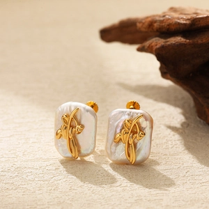 Detailed macro view of baroque pearl earrings with golden flower accents and screw-back closure