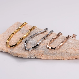 Polished stainless steel cube bracelets in gold, silver, and rose gold on natural stone