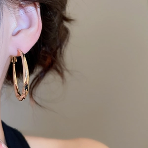 Close-up of elegant twisted gold hoop earrings worn by a model for a stylish casual look