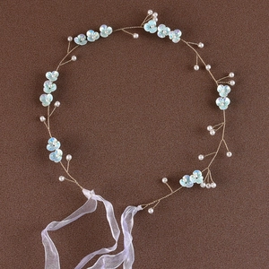 Detail of bridal headband with light blue flowers and white pearls on dark background