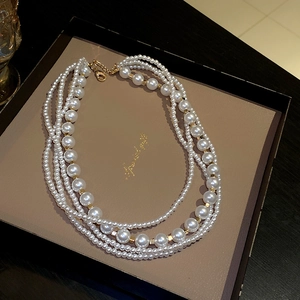 Detail view of multi-layer white pearl necklace with golden beads in a gift box
