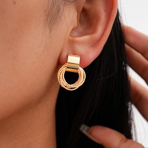 Close-up of gold layered metal rings earrings on model showing textured craftsmanship