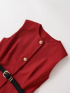 Detail of red sleeveless woven dress showing golden star-embossed buttons and black belt