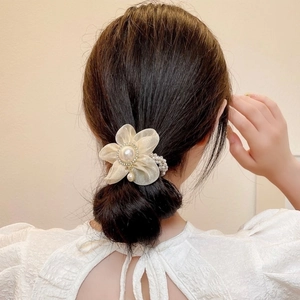 Détail du chouchou fleur en organza beige élégant avec perle centrale et petit pendentif