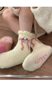 Close-up of thick coral fleece socks with cute dog embroidery and pink ribbon details
