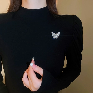 Detail of a sparkling butterfly brooch with teardrop zircons on black fabric background