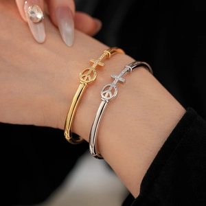 Close-up of gold and silver cross bangles with inlaid zircons on a model's wrist