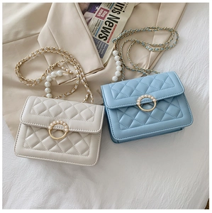 Detailed view of quilted chain bags with faux pearl accents and circular locks