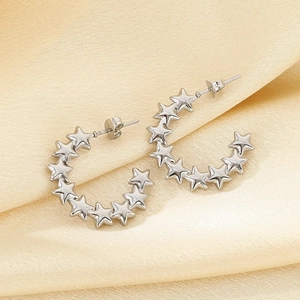 Macro shot of silver C-shaped stainless steel earrings featuring a row of carved stars