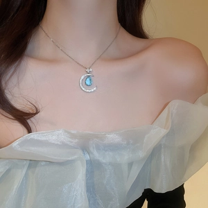 Close-up of elegant moon necklace with blue teardrop gemstone and sparkling zirconias