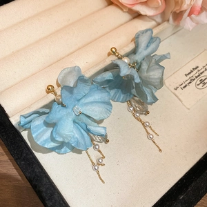 Detail of blue fabric flower earring with pearl and crystal tassels on jewelry tray
