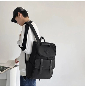 Detail view of a black nylon backpack with double leather straps and flap closure