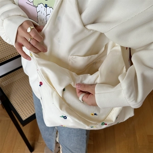 Detail of floral canvas tote bag featuring a secure interior zipper pocket and embroidery