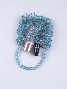 Macro detail of hand-beaded blue crystal clutch bag showing faceted acrylic beads and metal chain