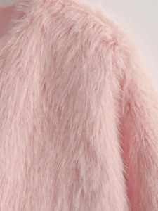 Détail de la texture de fausse fourrure rose sur l'épaule et la manche d'une veste