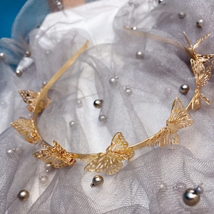 Detailed view of golden 3D hollow butterfly headband on elegant silver pearl mesh fabric